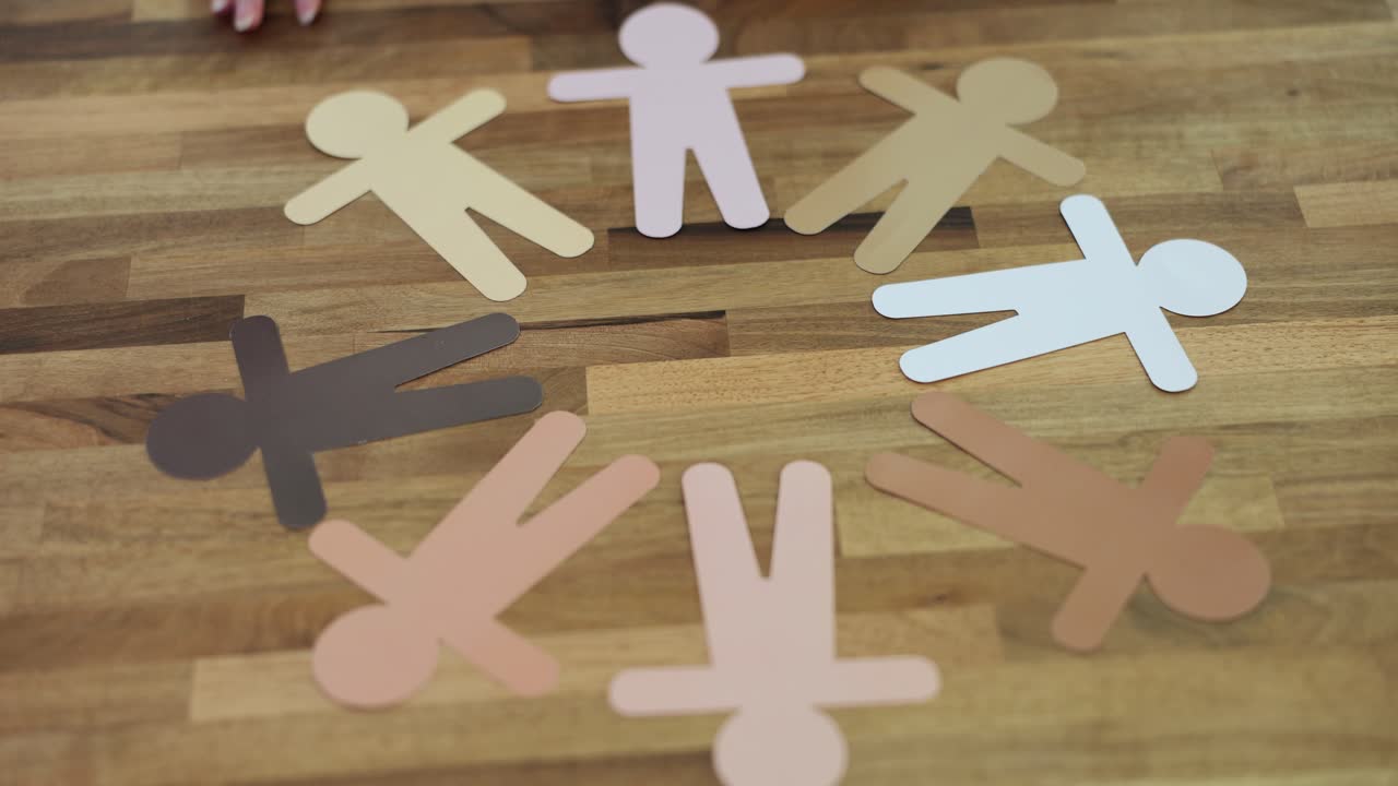 Diverse Paper Cut-Out People Arranged in a Circle on a Wooden Table
