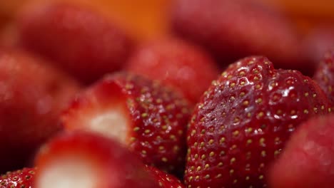 close up view of whole juicy red strawberries with green leaves cut off being processed at a factory