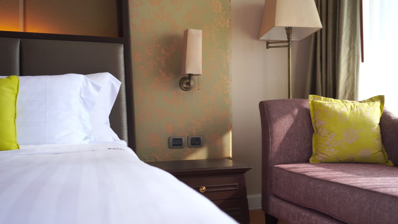 Zwenk naar links van een kamer in een luxe resort met bed en chaise longue.
