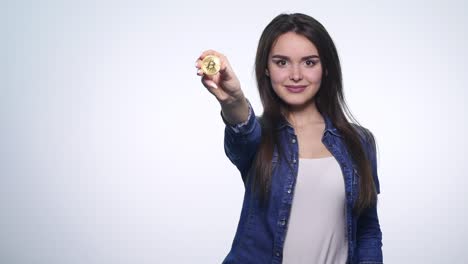 cerca de morena de moda sexy mujer bastante rica tiene un bitcoin dorado en las manos