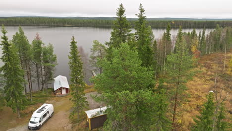 sweden - a lovely autumn forest in october, a picturesque lake, and a parked white campervan - aerial drone shot