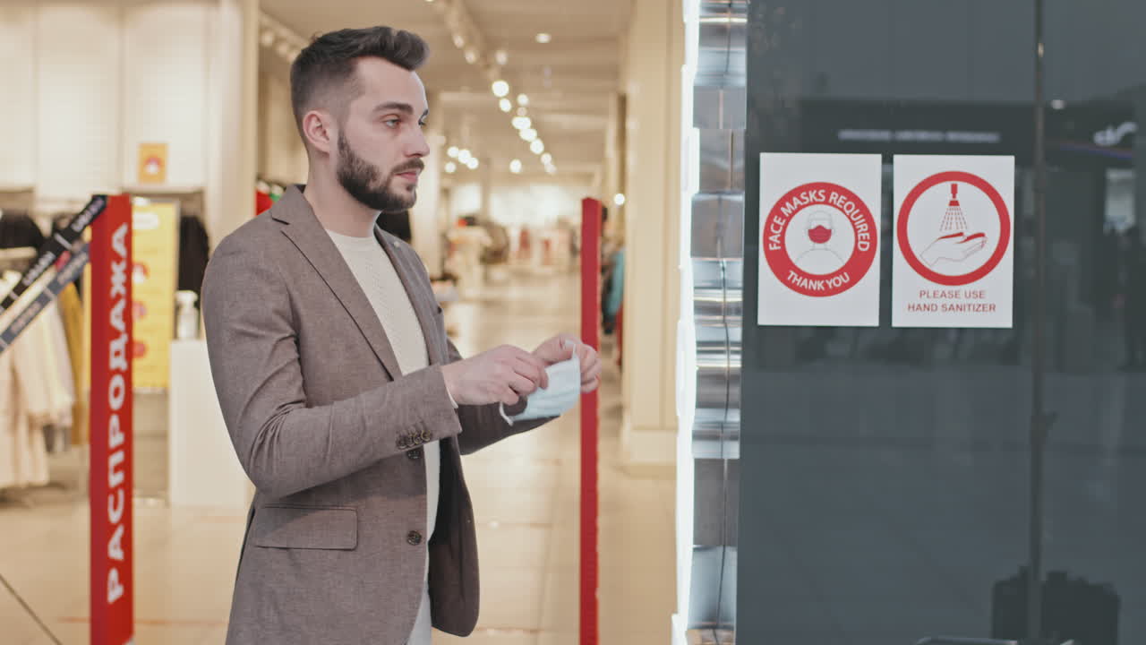 Man Putting On Face Mask Before Entering Clothing Store