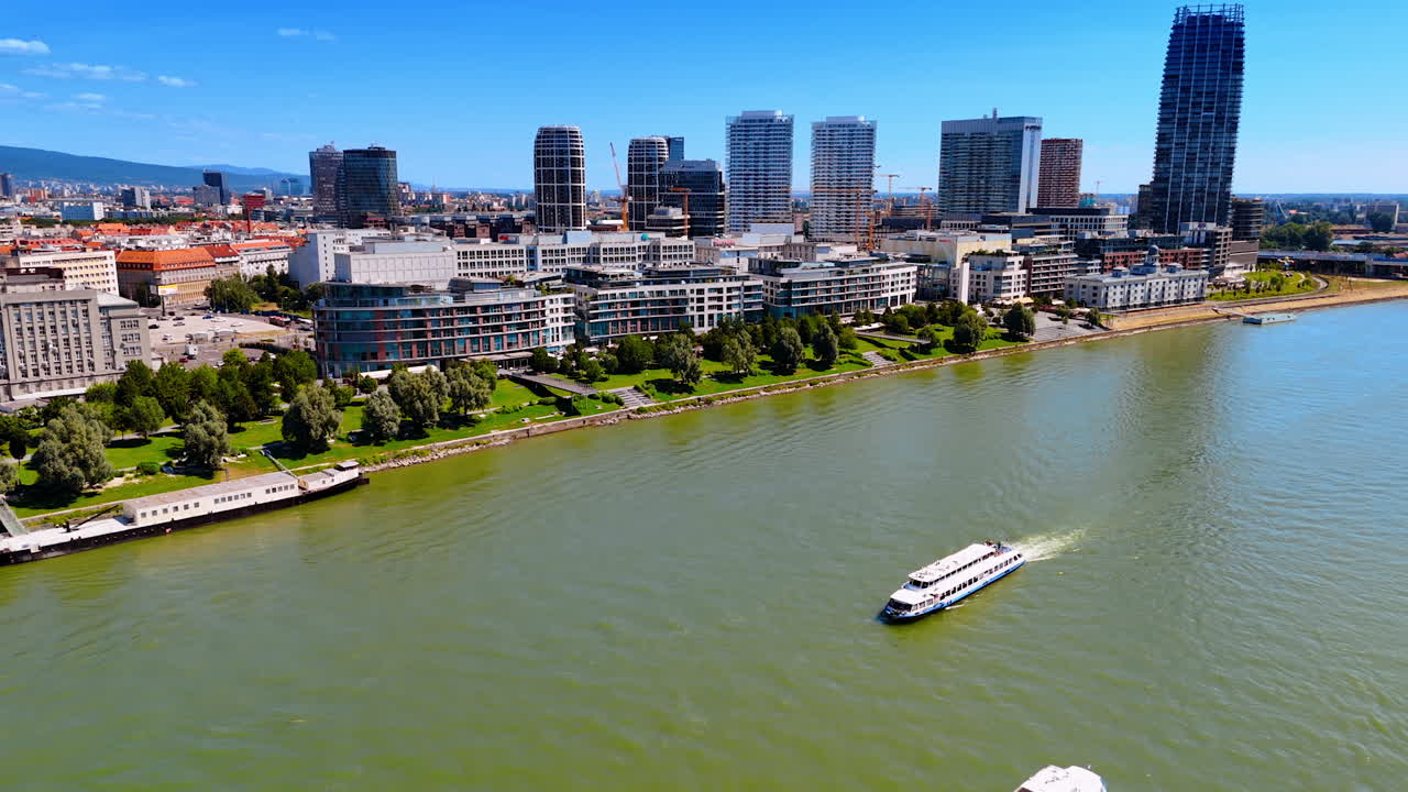 Boats move under the old bridge by the Danube. Modern skyline on the waterfront at backdrop. Bratislava, Slovakia