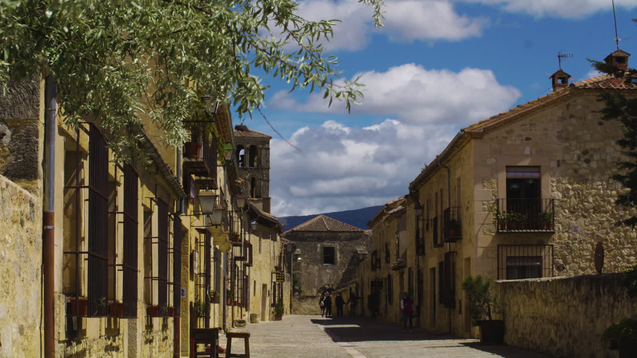 turistas caminando por la carretera rodeada de edificios medievales en la ciudad de pedraza en segovia, españa