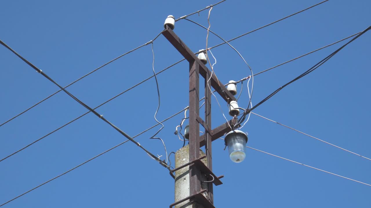 An electric pole with wires connected to it against a blue sky. Power supply of residential buildings.