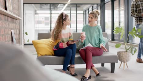 busy diverse businesswomen talking with takeaway coffee in office in slow motion