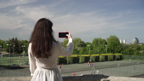 ロンドンのウィンブルドンの公園の写真を撮るかなりイタリア人女性観光客