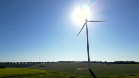 view of rotating wind turbine blades against the backdrop of the sun, renewable energy sources