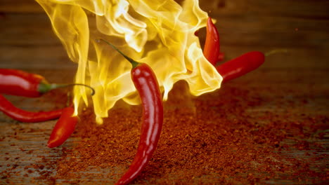 chili peppers thrown to a pile of chipotle powder on the table burst into flames, slow motion