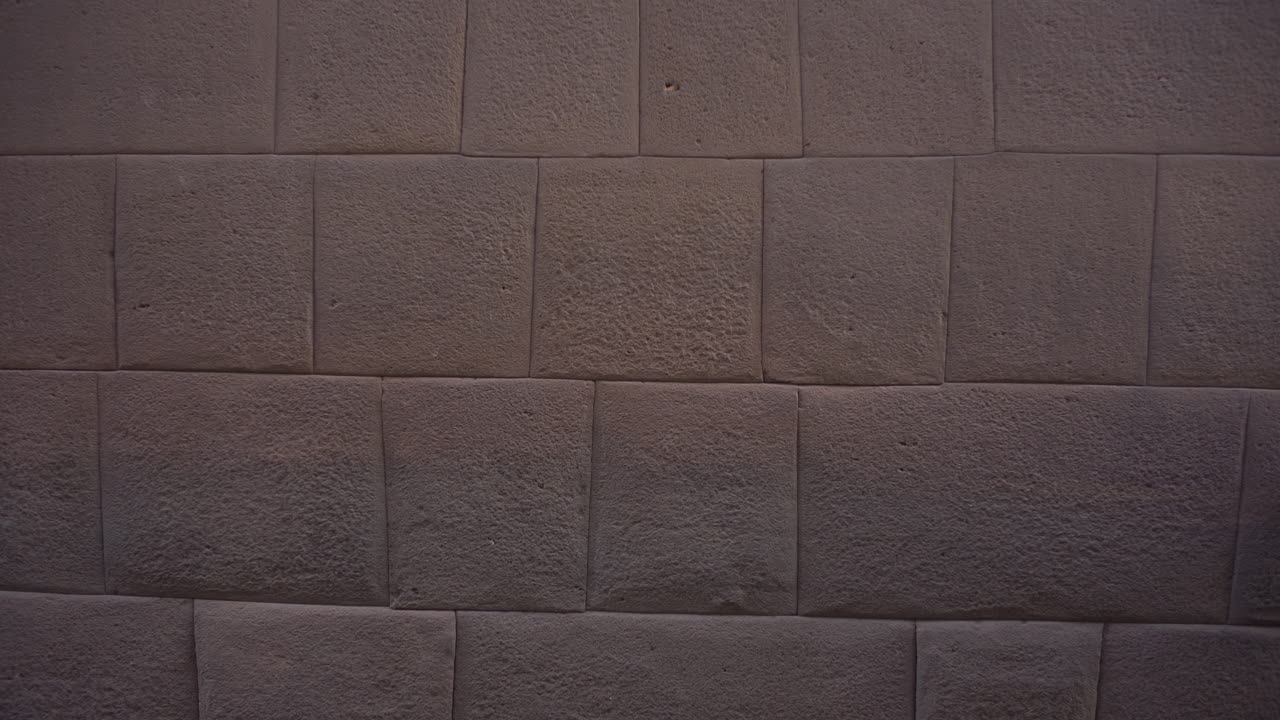 쿠스코 페루의 코리칸차 성벽을 통과하는 아시아 여성 관광객은 인카의 전형적인 석조로 만들어진 복잡한 절단으로 만들어진 원주민의 바위로 만들어졌습니다.