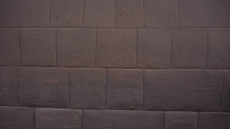 una turista asiática que pasa por las paredes de qorikancha en cusco, perú, hechas de rocas indígenas hechas con sus intrincados cortes, que es la típica mampostería de los incas.