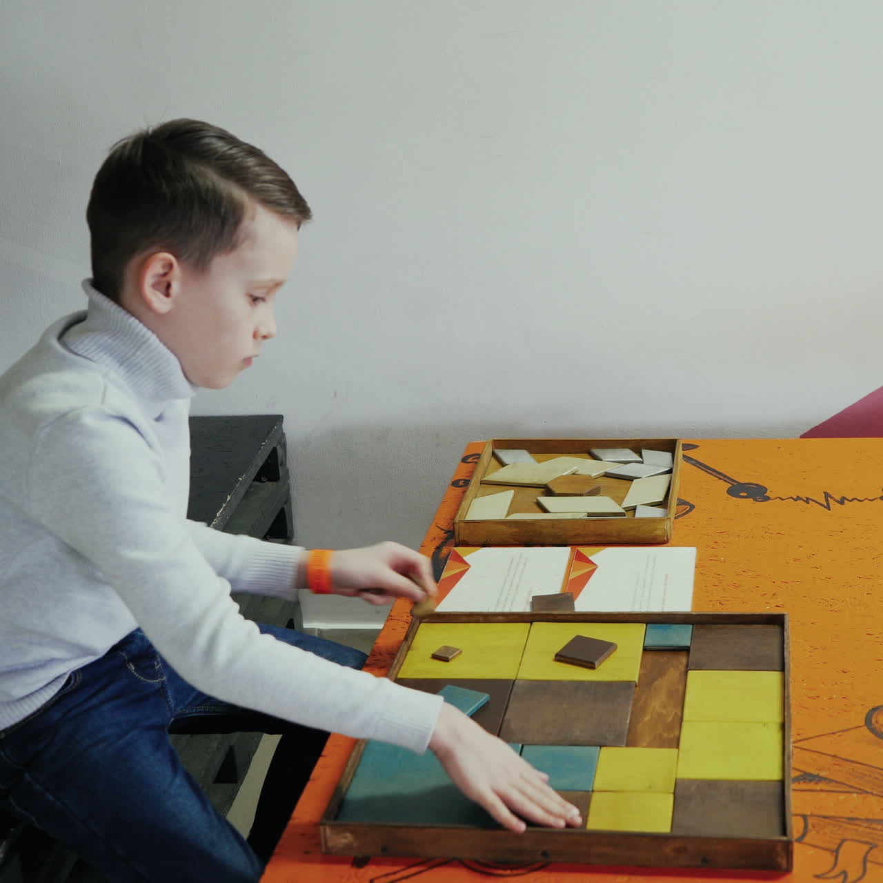 Boy playing with a puzzle of wood. Kid in the scientific center. Square video