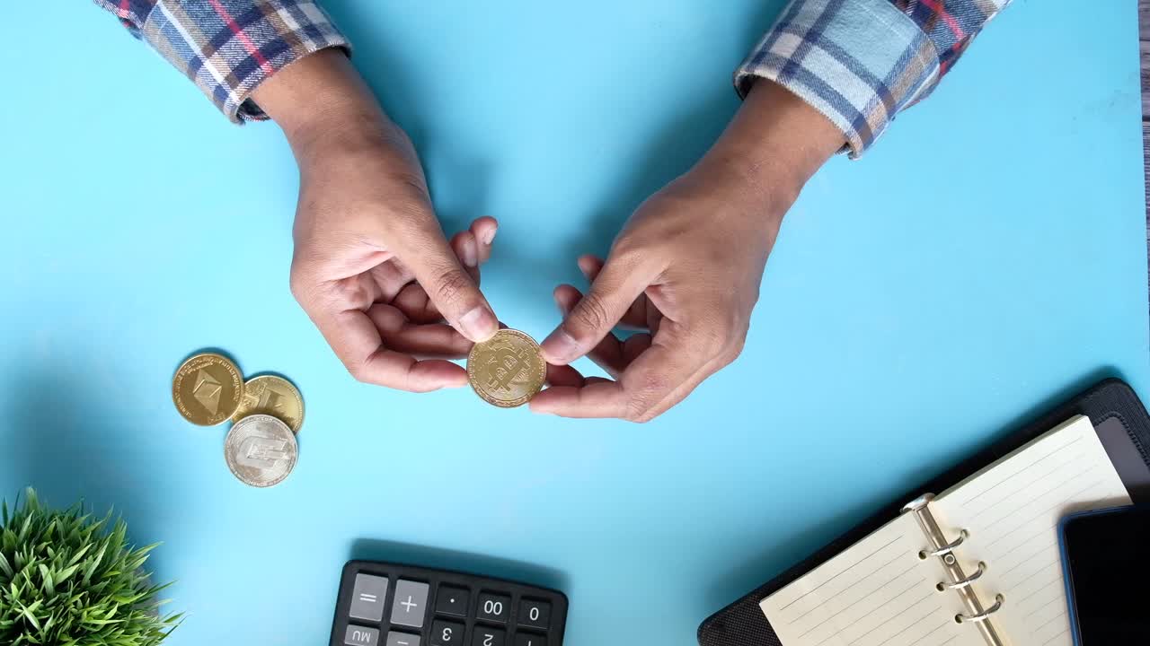 Persona che tiene una moneta Bitcoin su una scrivania