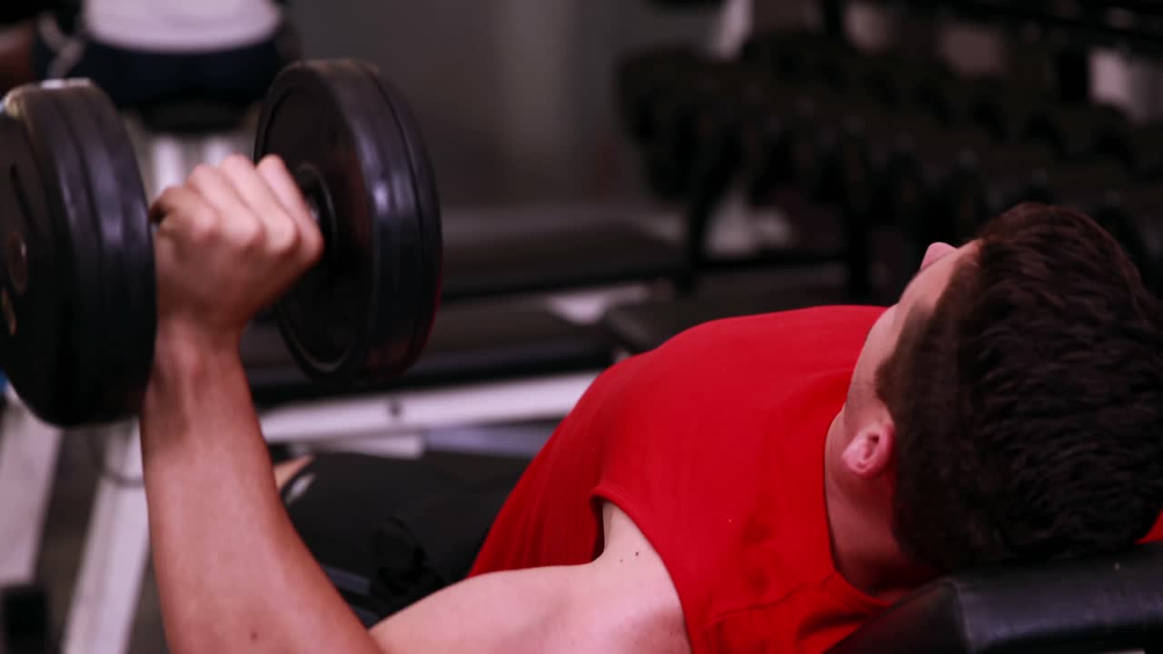 벤치 에 누워 있는 덤벨 을 들어 올리는 적당 한 사람