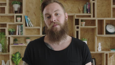 close up portrait of handsome young hipster man with beard looking serious pensive at camera