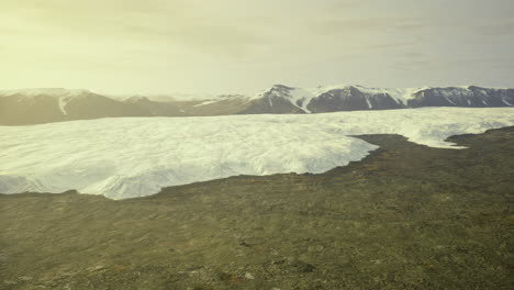 Vast glacier melting into rocky terrain under soft sunlight