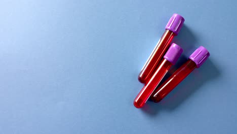 Close-up-of-blood-samples-on-blue-background-with-copy-space,-slow-motion