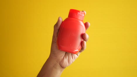 hand holding a small red plastic bottle