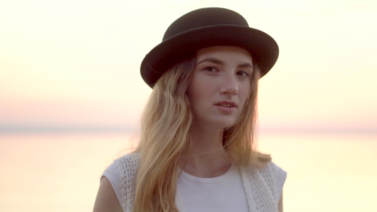 mujer con sombrero negro al atardecer