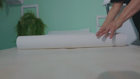 professional masseuse covering massage table with disposable sheet