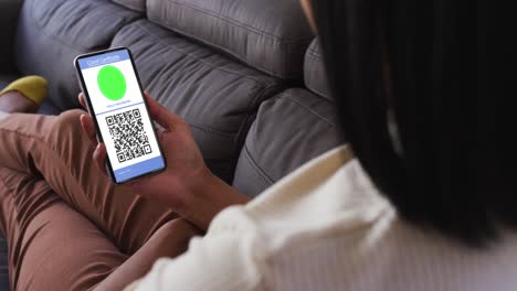 mujer en casa con un teléfono inteligente con certificado de vacunación contra la covid y código qr en la pantalla