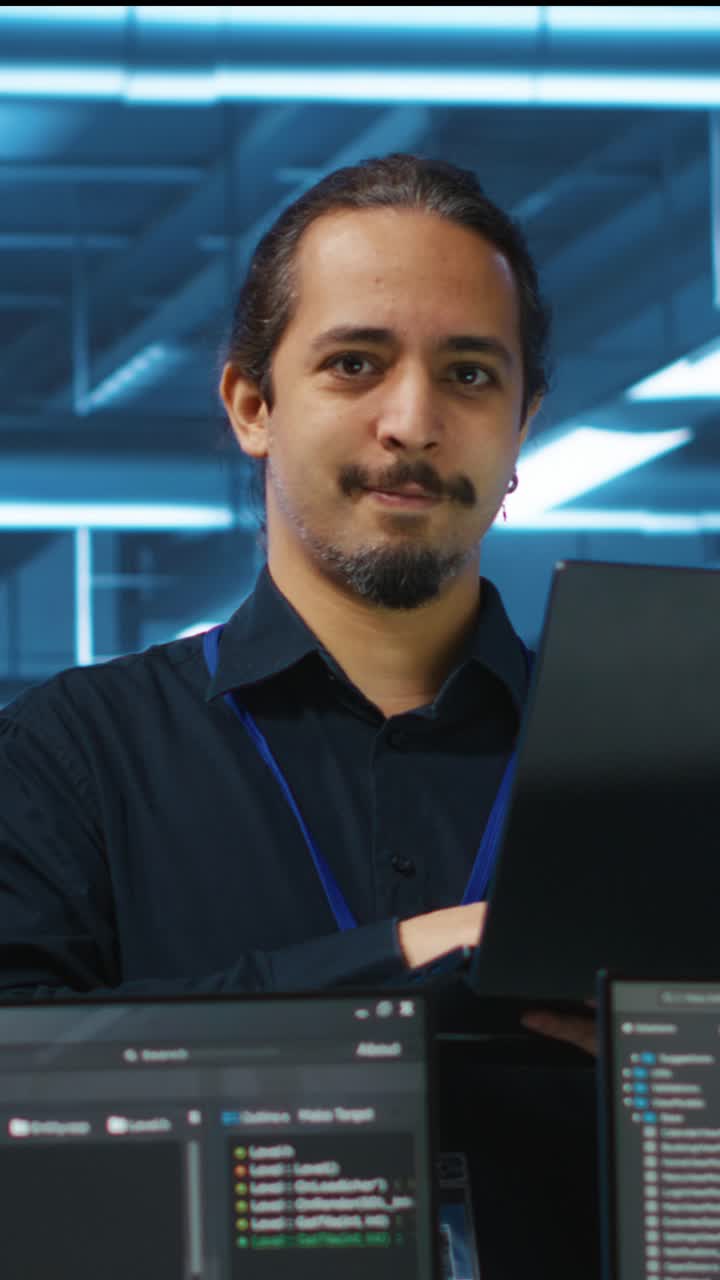 Focused IT Specialist Working on Laptop and Smiling in Data Center
