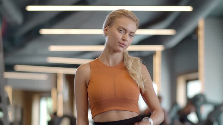 una ragazza atleta seria che controlla i risultati in palestra. una sportiva in piedi in un club sportivo.