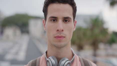 close up portrait attractive young hispanic man looking serious male student in urban city background