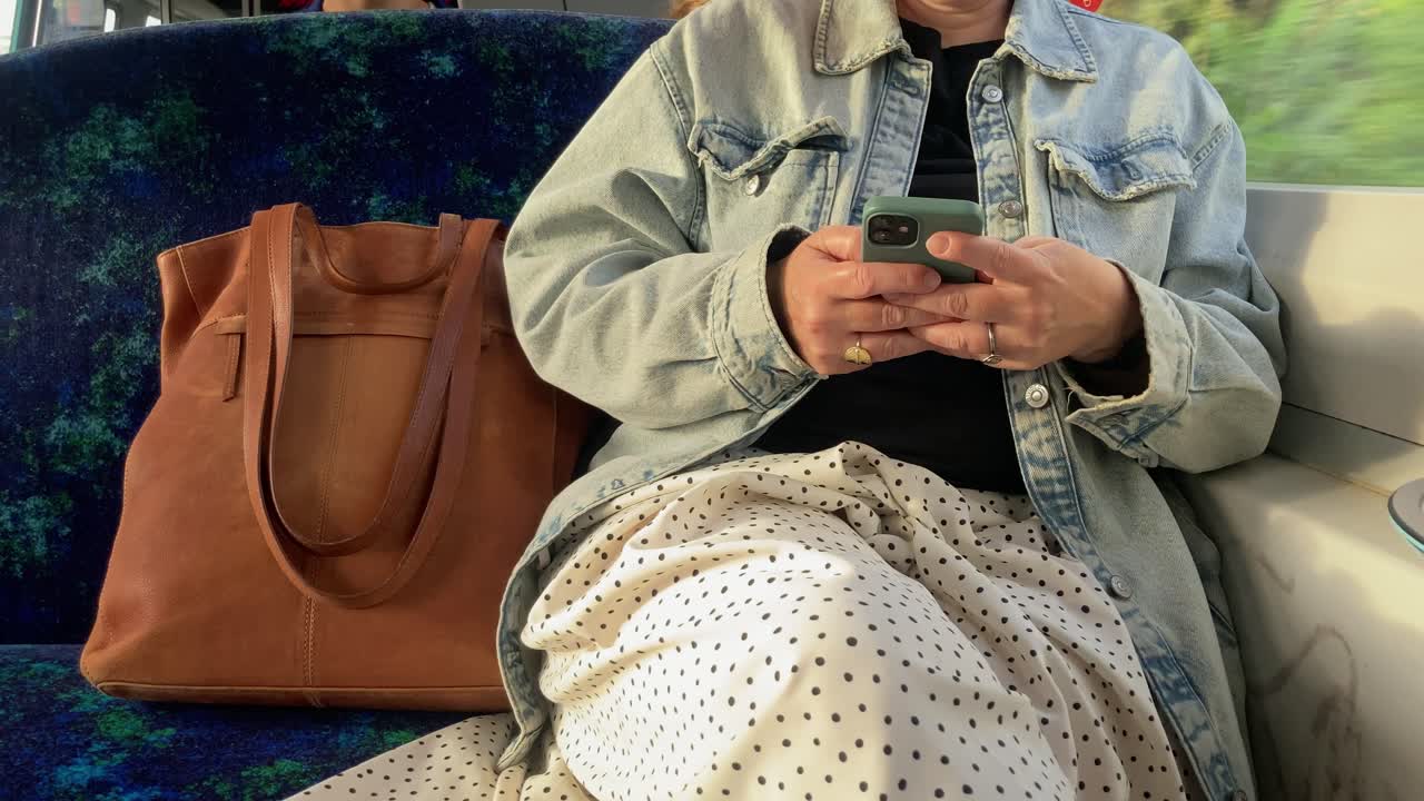 mujer no reconocida mirando el teléfono mientras está sentada en el tren, metro