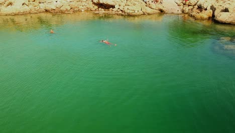 Drone-footage-of-a-model-floating-in-a-salt-water-natural-pool-lake-in-Greece