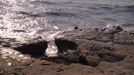 Slow-motion-view-of-waves-crashing-onto-small-cliffs-in-ocean