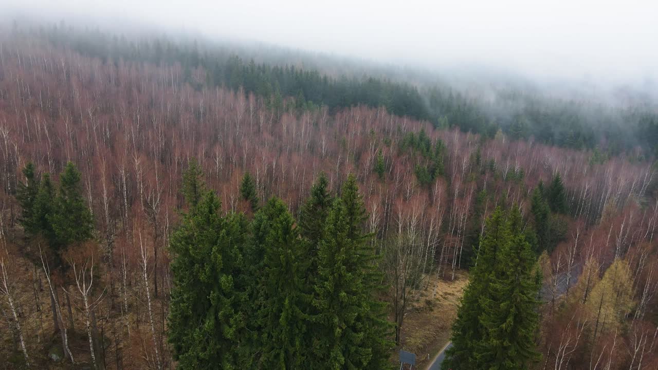Ilmakuva vuoren yli kulkevasta asfalttitiestä sumun keskellä