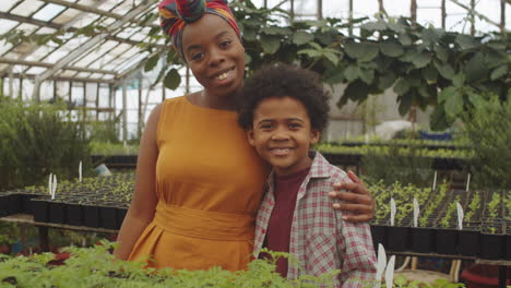 portrait of joyous african american mother and son in greenhouse