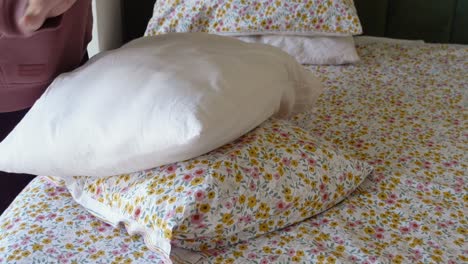 a woman making a bed with a floral duvet cover