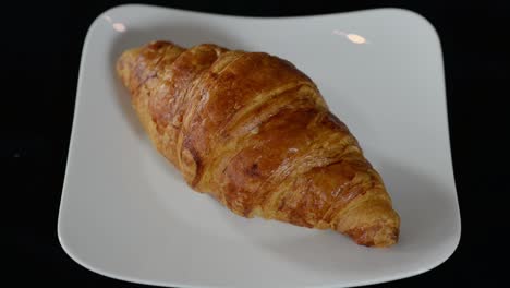 sabroso desayuno de croissant de mantequilla francesa en plato blanco sobre mesa negra, primer plano