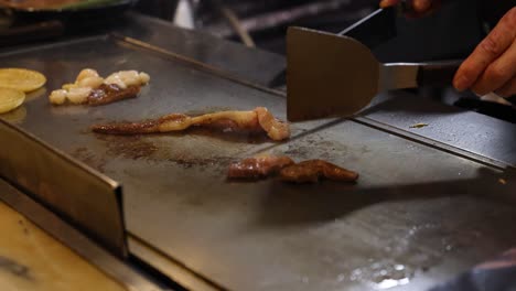 chef skillfully grilling meat on teppan