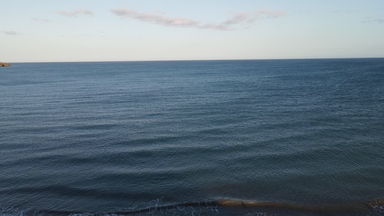 toma aérea de drones de una mujer parada en un acantilado frente al océano, islas canarias, fuerteventura