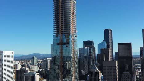 climbing aerial of a glass skyscraper being constructed in downtown seattle