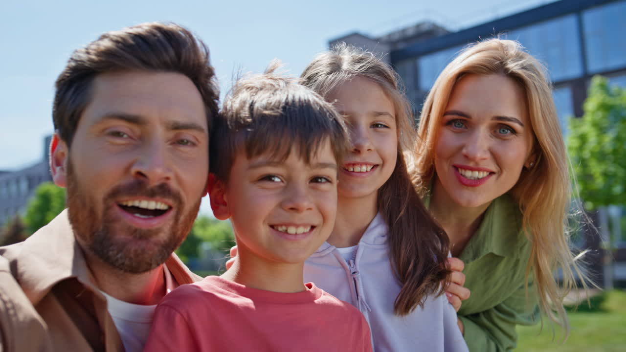 푸르른 동네에서 카메라를 보며 손을 흔드는 가족 화상 통화