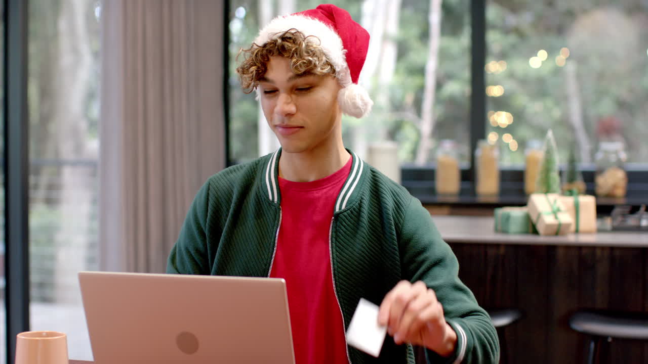 Asian man in Santa hat using laptop at home during Christmas season