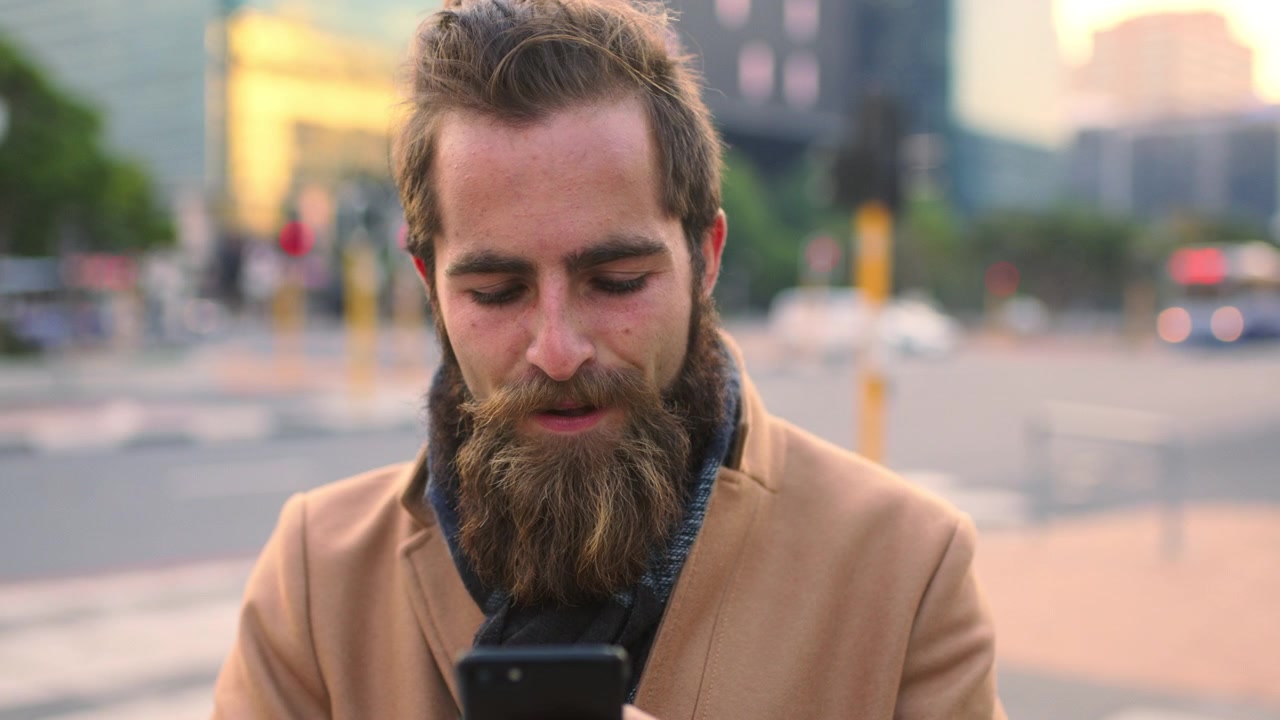 Young Man With Beard Using Smartphone on City Street