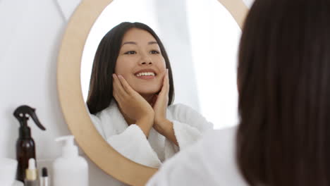 woman checking appearance in bathroom mirror
