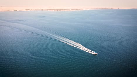 boat crusing on damman coast at the east of saudi arabia. the city next to it is al khobar