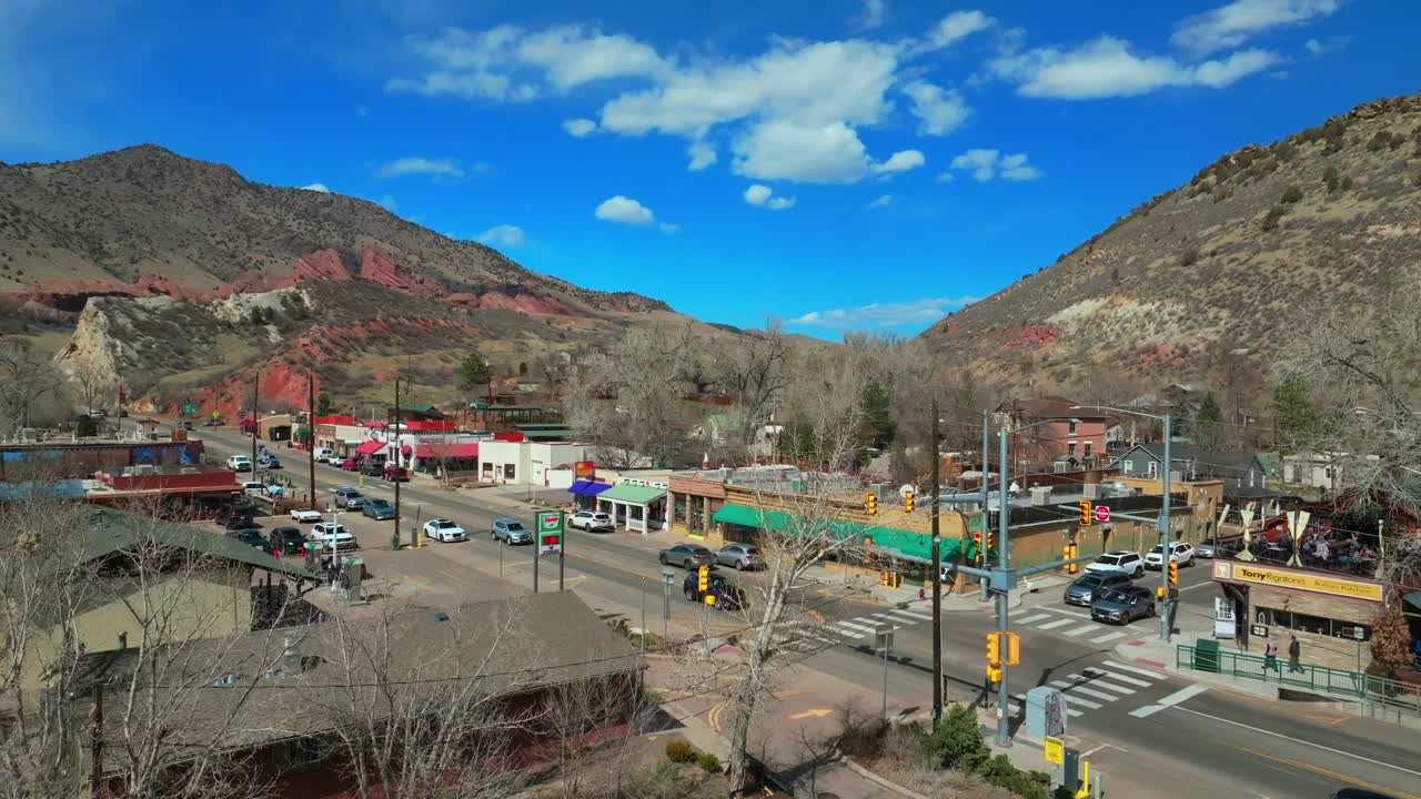 Winter downtown Main Street Morrison Colorado aerial drone Red Rocks Park and Amphitheater Mount Morrison Bear Creek sunny blue sky cloudy neighborhood traffic car driving historic town upward motion