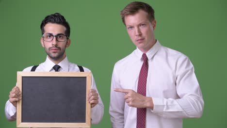 two young multi-ethnic businessmen working together against green background