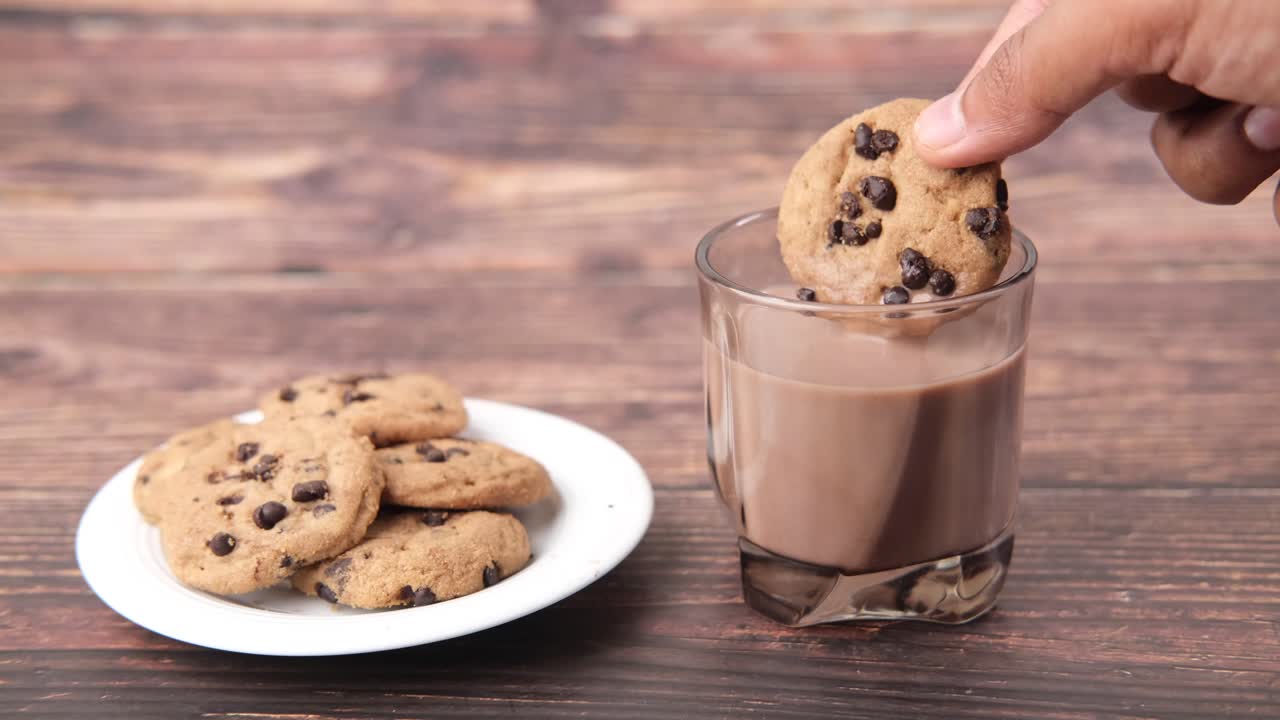 Intingere un biscotto con gocce di cioccolato nel latte al cioccolato