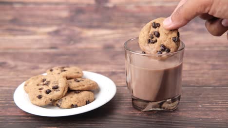 dipping chocolate chip cookie in chocolate milk