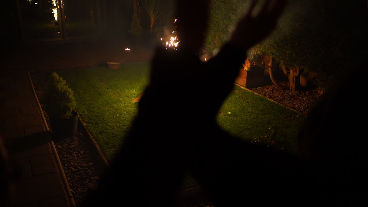 무장 연기와 밝은 깜박이는 색상을 흔드는 사람들과 함께 마당에서 불꽃놀이