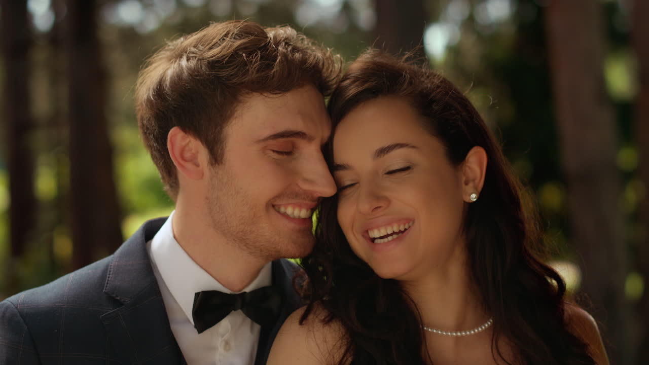 novia y novio alegres mirando a la cámara en el jardín. pareja de pie en el parque