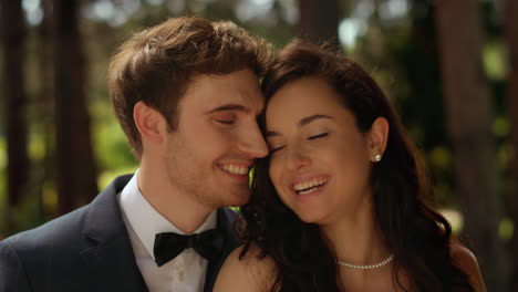 joyful bride and groom looking at camera in garden. couple standing in park